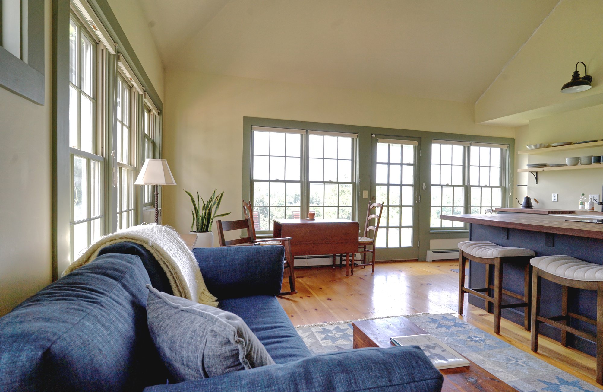 Living area with blue sofas, wood coffee table, French doors to the patio, and seating at the kitchen island.